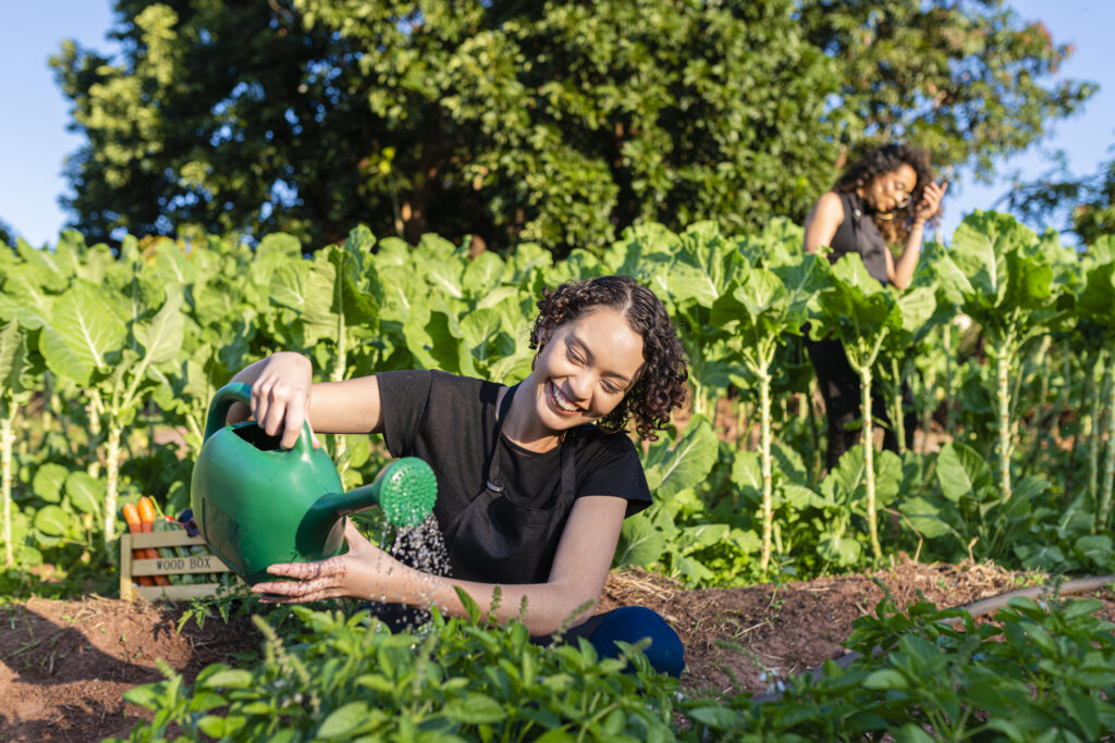 Girl watering organic products in her vegetable garden.