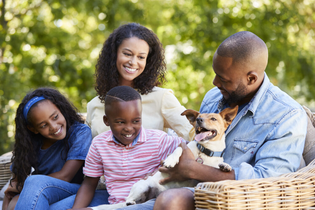 Parents and two kids sitting with pet dog in the garden