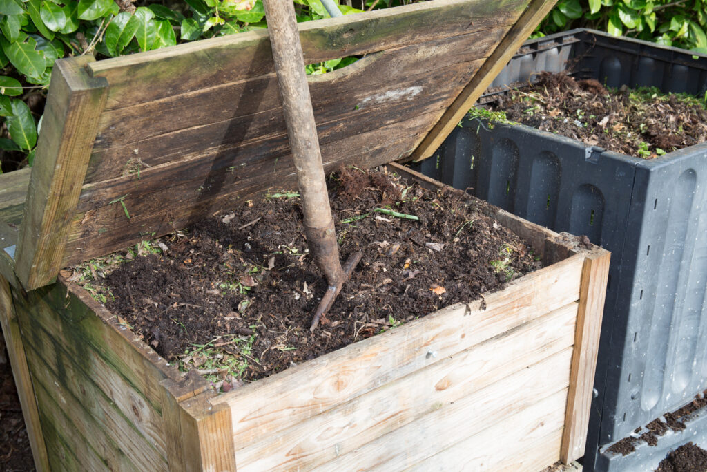 A wooden compost bin with the lid open