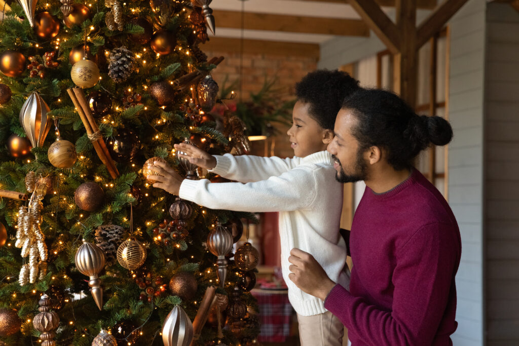 Loving African American father with little son decorating Christmas tree