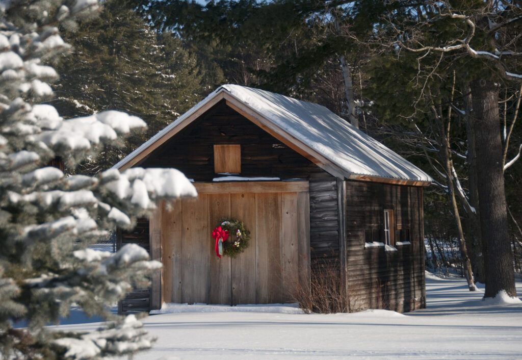 Country barn with holiday wreath in after fresh snowfall.