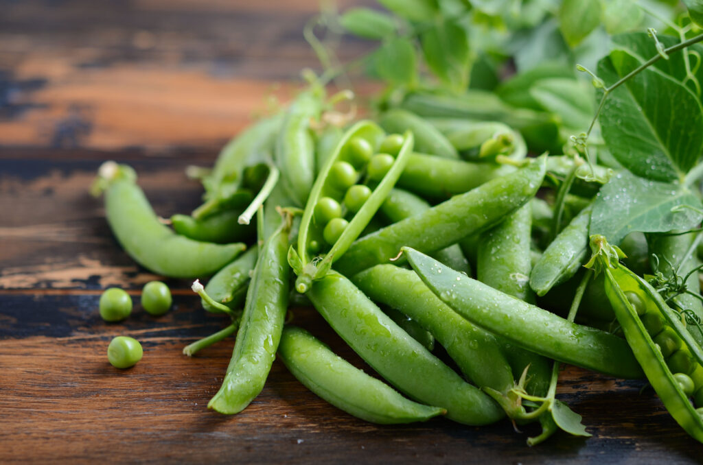 Fresh organic green peas on rustic wooden background, selective focus.