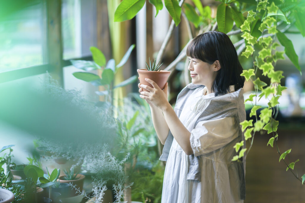 A woman standing next to the window with her houseplants