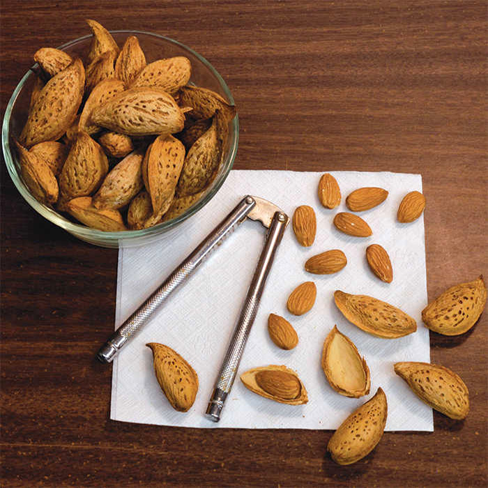 Almonds in a bowl and on the table being cracked open