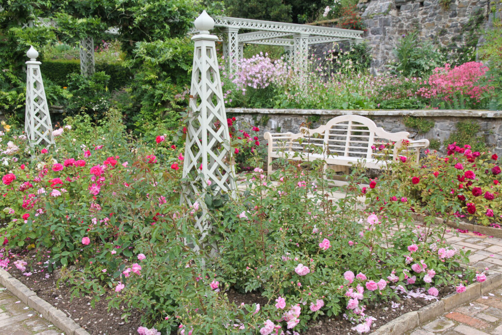 obelisk in the garden surrounded by pink and red flowers