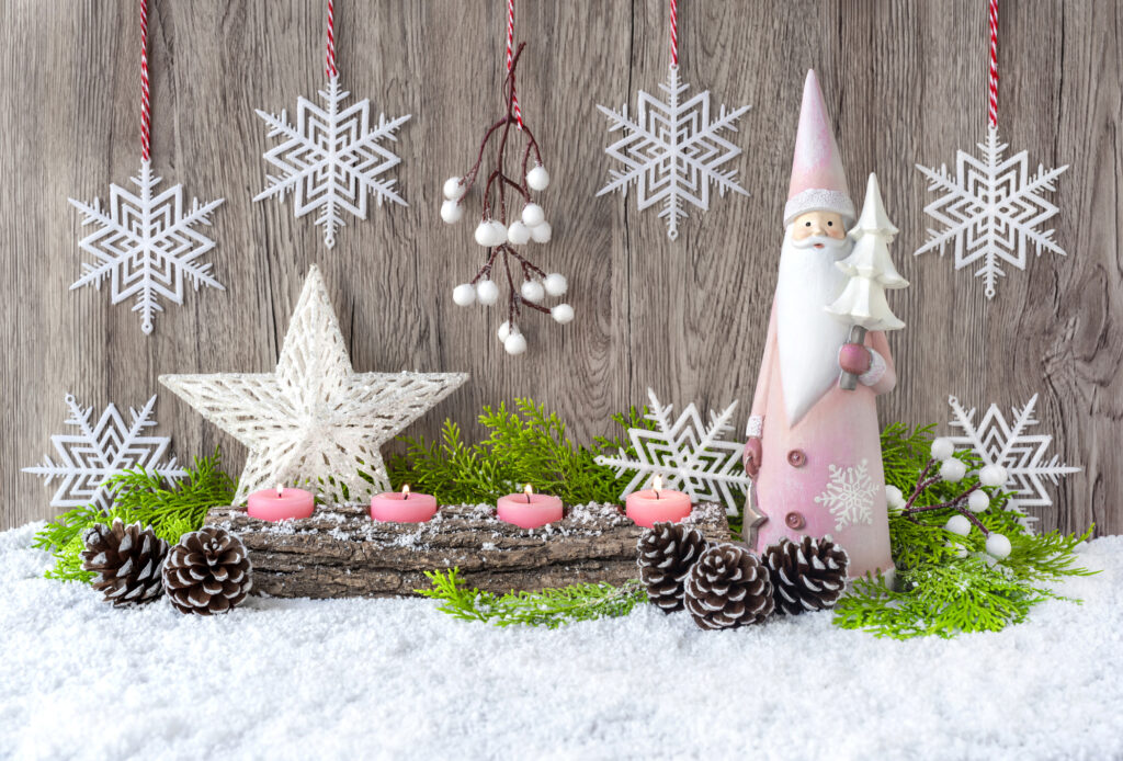 Advent candles, Santa Claus and a star in the snow are decorated with spruce branches. Christmas and New Year decor. Grey wooden background.