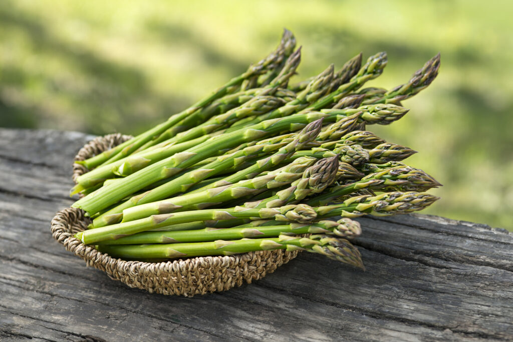fresh picked asparagus in a wicker basket on a wooden table