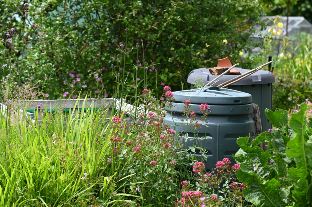 Compost bins next to flowers and garden