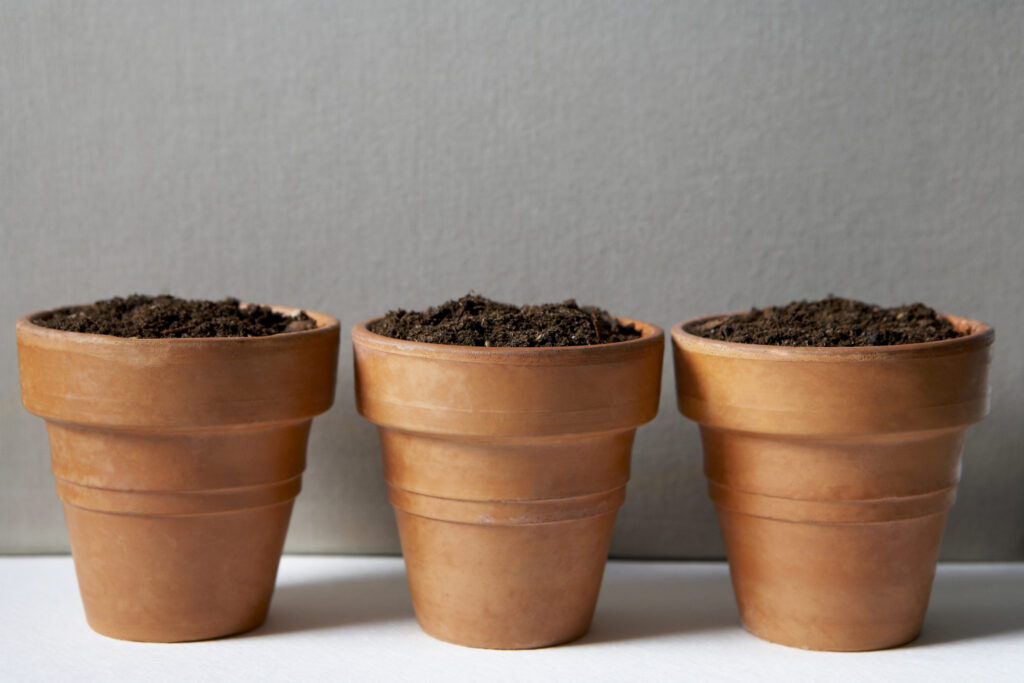 Three Terra Cotta pots filled with soil.